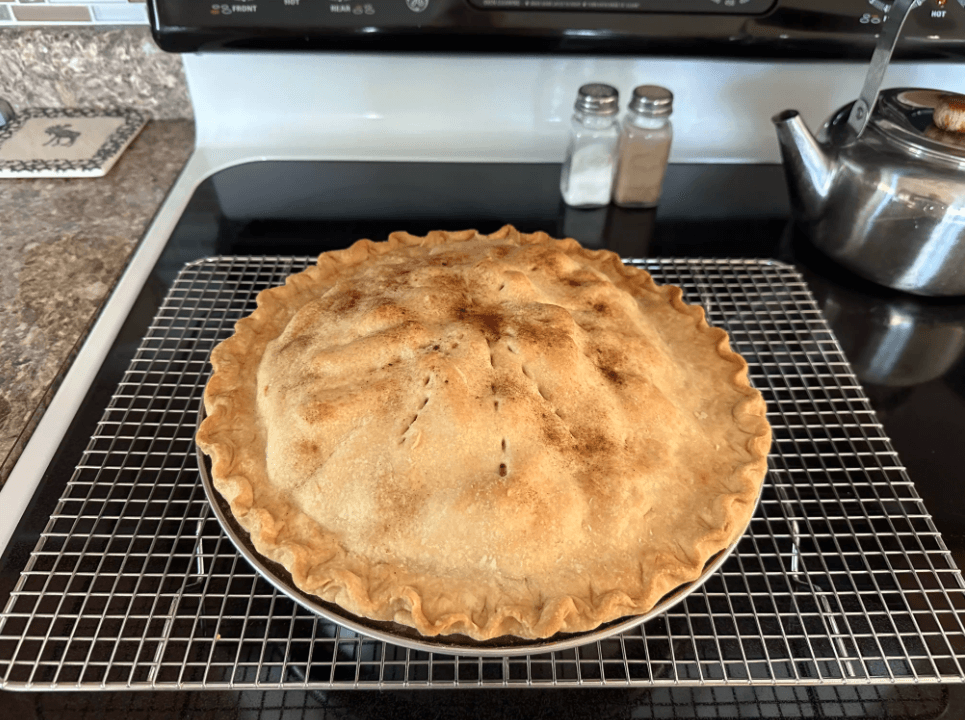 Close-up of a baker’s hands using a pastry cutter to prepare pie crust dough, surrounded by flour, butter, and utensils.