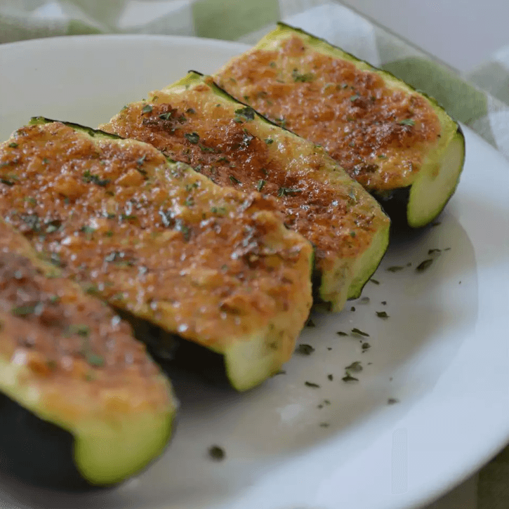 Zucchini parmesan with melted cheese and tomato sauce, garnished with fresh basil