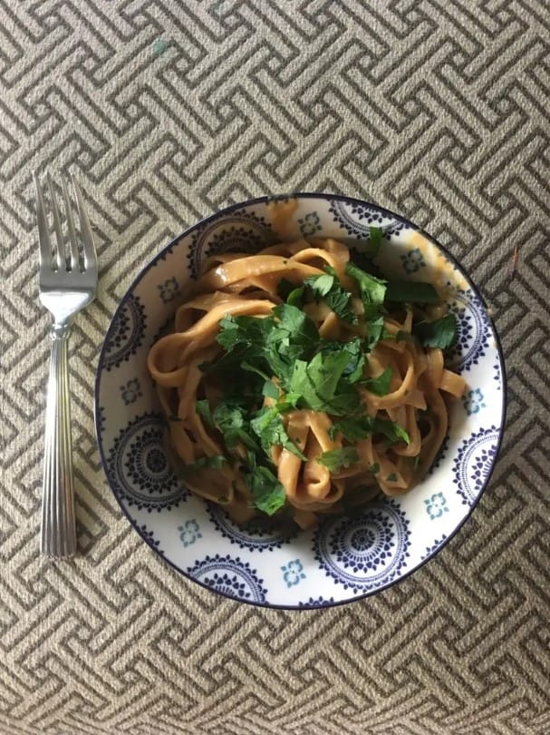 A bowl of creamy garlic Parmesan chicken pasta with a garnish of parsley