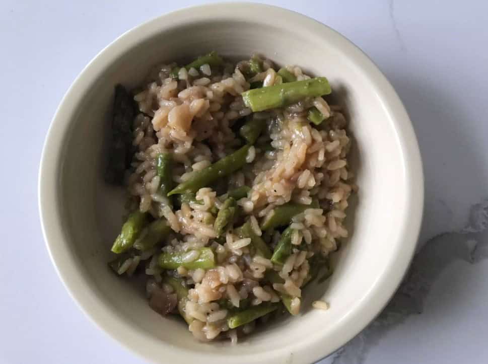 A creamy bowl of risotto garnished with parsley, served with a side of wine. is risotto gluten free