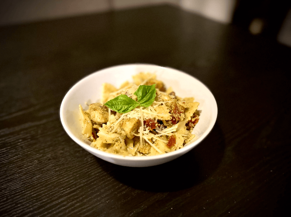 A plate of pasta with grilled chicken and Alfredo sauce, garnished with parsley.