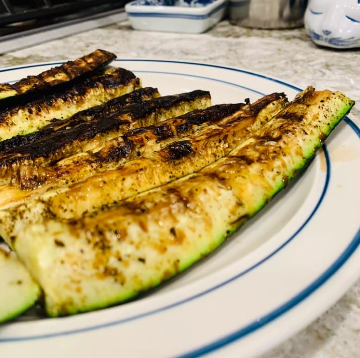 Fresh zucchini slices being salted on a tray A realistic depiction of zucchini slices spread on a tray with salt evenly sprinkled on them, representing the salting process.